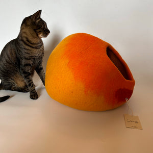 Tabby cat sitting beside the Cozy Felt Cat Cave, showcasing the gradient sunset design. Stylish and comfortable cat hideaway made of handmade wool felt.