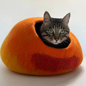 Close-up of a tabby cat looking out from the Cozy Felt Cat Cave. Gradient sunset-inspired cat hideaway made of premium handmade wool felt.