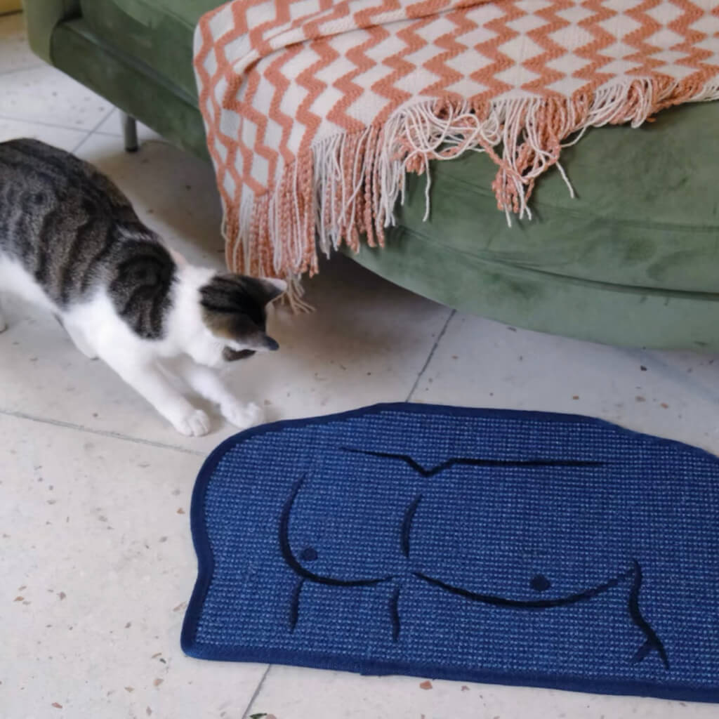 Cat playing near a sisal mat with a unique embroidered man chest design on the floor.