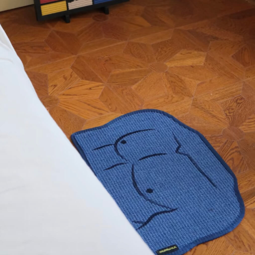 Sisal cat scratching mat with fun embroidered man chest design placed on wooden floor.