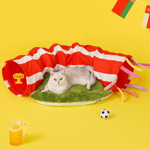 Cat resting on the grass-textured bed with the ZEZE Football Field Cat Tunnel Toy.