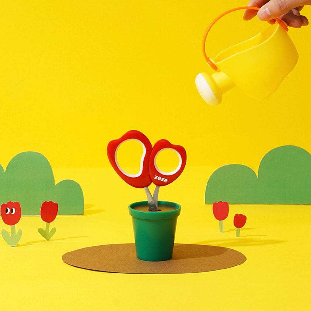 Hand holding ZEZE Tulip-Shaped Pet Nail Clippers with a watering can in a playful grooming scene.