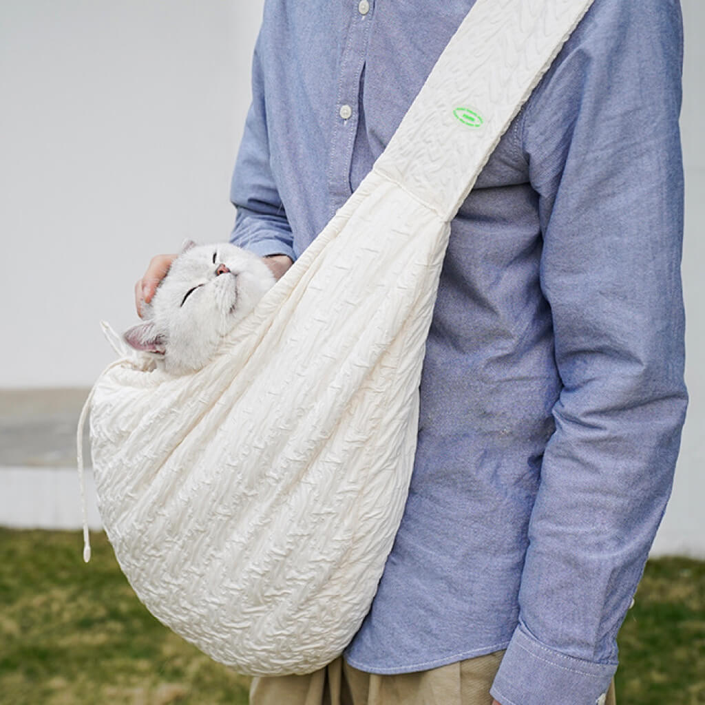 Pet owner holding a cat in a Crossbody Pet Travel Bag, designed for comfort and style during outdoor adventures.