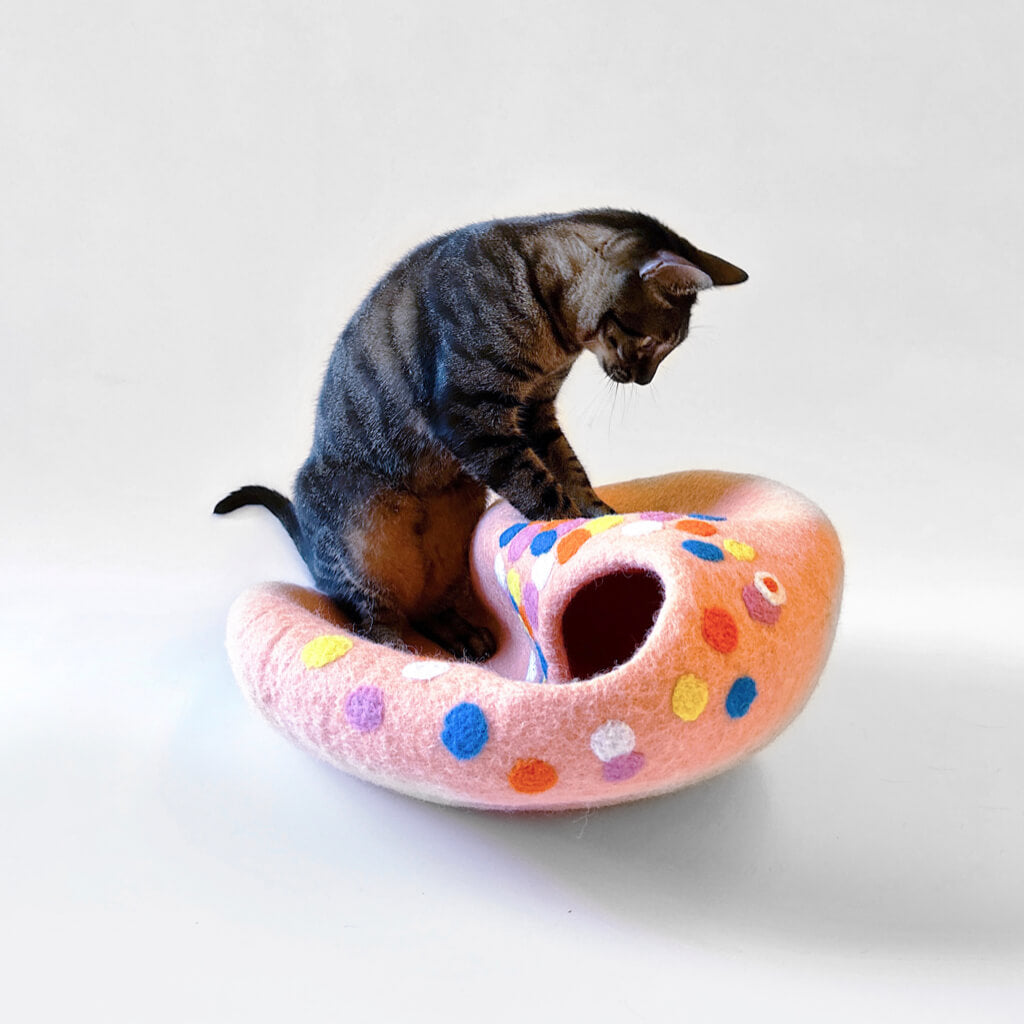 cat playing with a peach-pink polka dot felt cat cave, showcasing the cave's fun and versatile design.