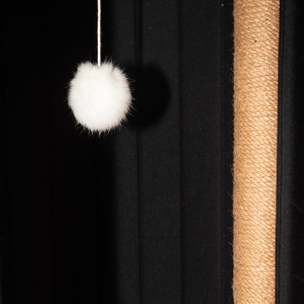 Close-up of the fluffy white ball hanging inside the Time Travel Cat Tower for interactive play, a sisal post for cat to scratch.