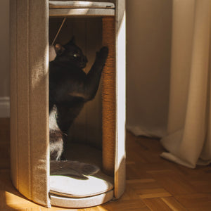 Close-up of a black cat scratching the sisal post inside the beige Time Travel Cat Tower, highlighting the interactive features for cats.