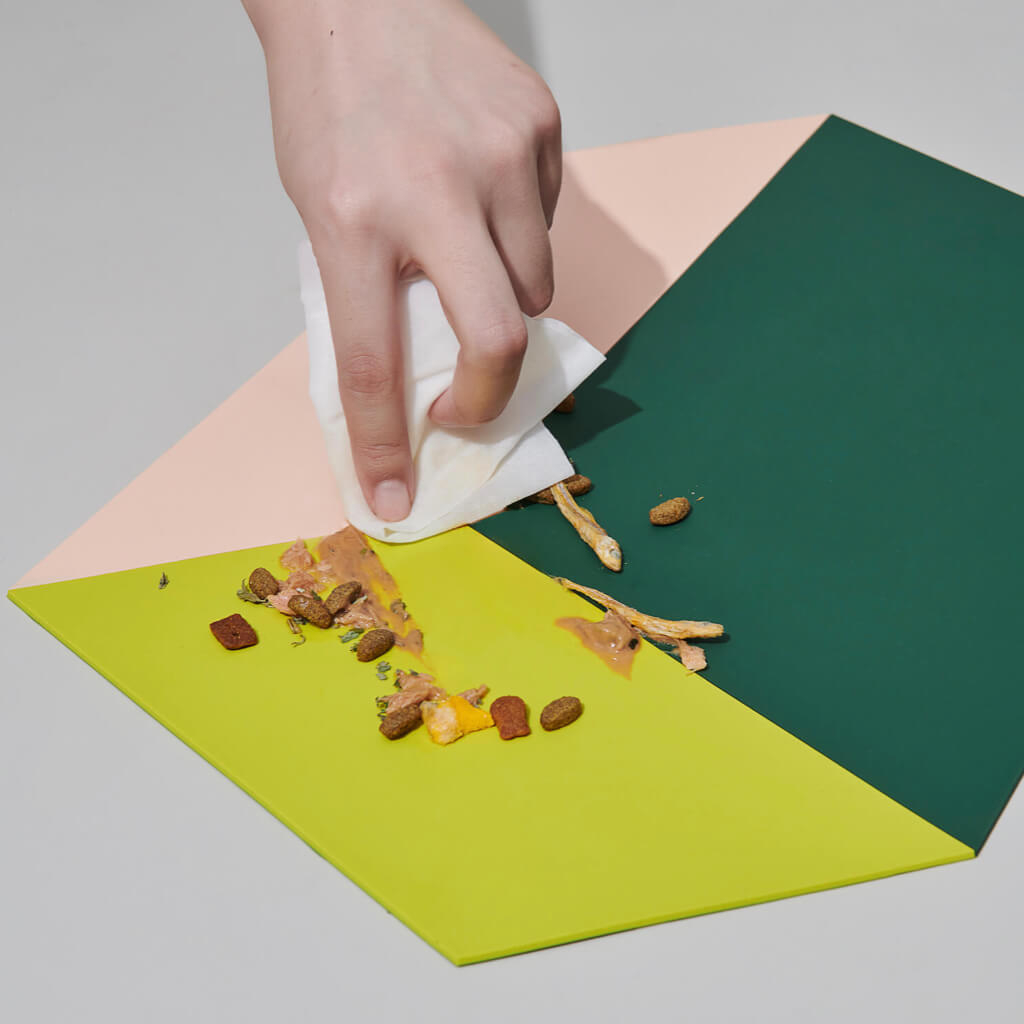 Wiping down the Chroma Party Pet Dining Mat - #Power Green with food spills.